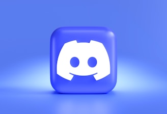 A three-dimensional blue cube featuring a white, stylized gaming controller symbol associated with a popular communication platform, set against a gradient blue background.